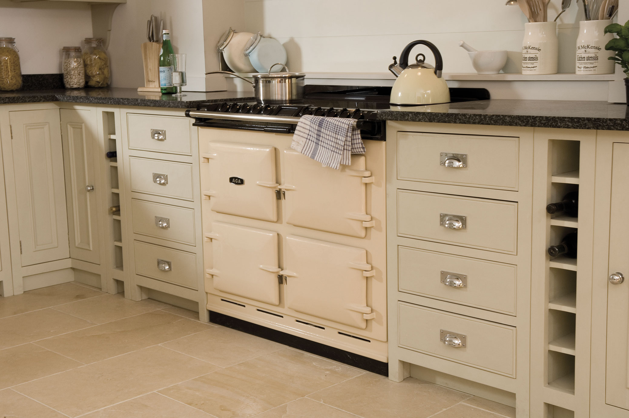 Klassischer cremefarbener AGA-Herd in einer stilvollen Landhausküche mit modernen Details Cremefarbener AGA-Herd mit Topf und Wasserkocher in einer eleganten Landhausküche mit cremefarbenen Schränken und Steinboden