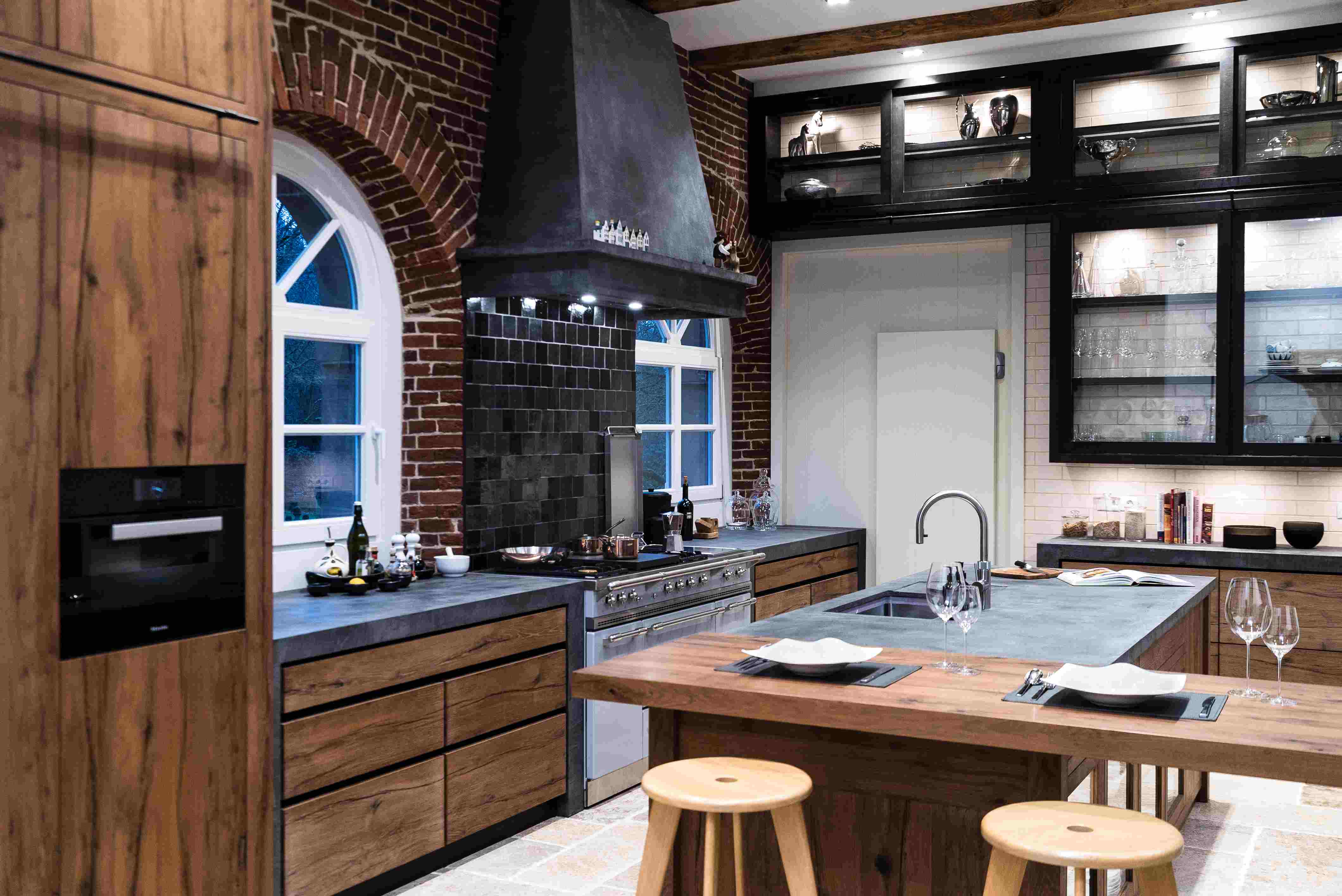 Moderne Loftküche aus Holz und Edelstahl mit Kücheninsel und Bartresen Offene Designerküche mit Holzfronten, zentraler Kochinsel, Bartresen, Hockern und stilvollen schwarzen Elementen
