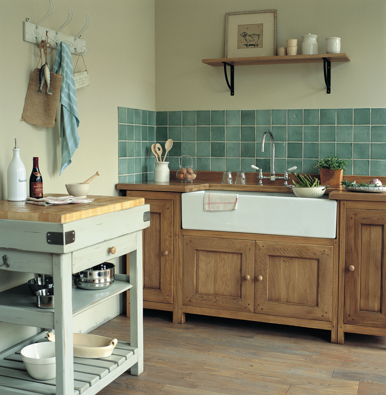 Landhausküche mit Holzmöbeln und grünen Fliesen, inklusive Spüle und Küchenutensilien Gemütliche Landhausküche mit Holzschränken, grünen Wandfliesen, einem Spülbecken, Kücheninsel, Kochutensilien und Dekorationen