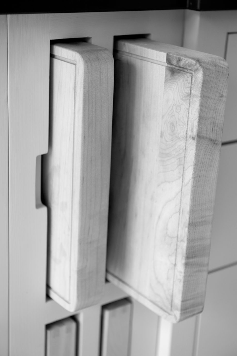 Praktischer Steckplatz für Schneidebretter in einer modernen Küchenaufbewahrung Zwei massive Holzschneidebretter sind platzsparend in einem senkrechten Steckplatz in einem Küchenschrank untergebracht.