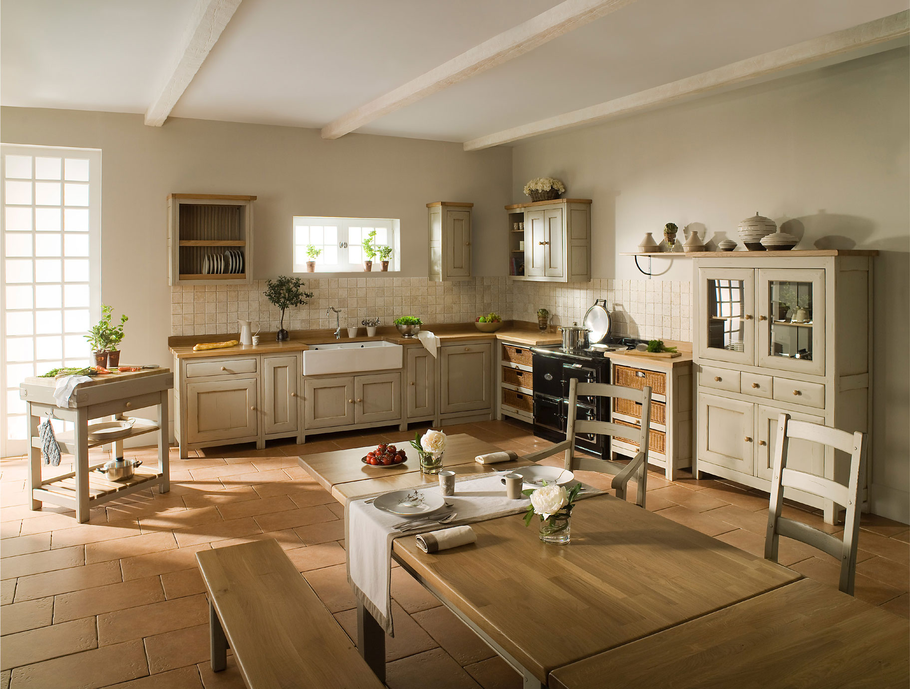 Landhausküche mit Holzmöbeln, Esstisch und geschmackvoller Dekoration Helle Landhausküche mit cremefarbenen Schränken, Holztisch, Sitzbank, modernem Herd und dekorativen Pflanzen