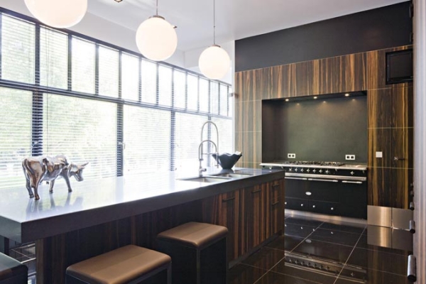 Moderne Küche mit Kochinsel und eleganter Holzoptik Helle moderne Küche mit großer Kochinsel, Holzdekor, Hockern, großen Fenstern und Design-Accessoires