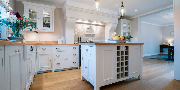 Moderne Landhausküche mit Kücheninsel aus Holz und stilvollen Hängeschränken Helle Landhausküche mit Holzarbeitsflächen, Kücheninsel, weißen Schränken und dekorativen Details