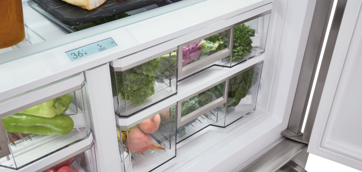 Gemüsefächer eines modernen Kühlschranks mit frischem Obst und Gemüse Offener Kühlschrank mit verschiedenen frischen Gemüsesorten in transparenten Schubladen