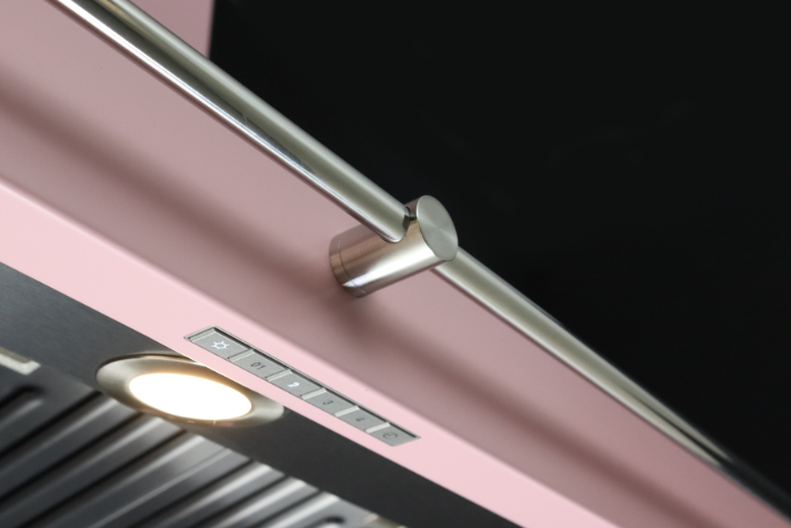 Detailansicht einer modernen Dunstabzugshaube in Rosa mit Edelstahlgriff und Bedienelementen Moderne Dunstabzugshaube in Rosa mit Edelstahlgriff, Bedientasten und integrierter Beleuchtung
