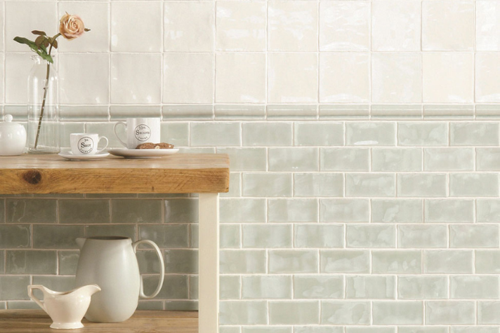 Helle Küchenfliesen im Landhausstil mit Holzregal, Vase und Geschirr Küche mit hellen Wandfliesen in zwei Farben, Holzregal, Tassen, Krug und Vase mit Rose