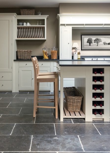 Moderne Landhausküche mit heller Kücheninsel, Weinstaufläche und Holzstuhl Helle Landhausküche mit Kücheninsel, Holzstuhl, Weinfächer, Geschirrkorb und hochwertigem Fliesenboden