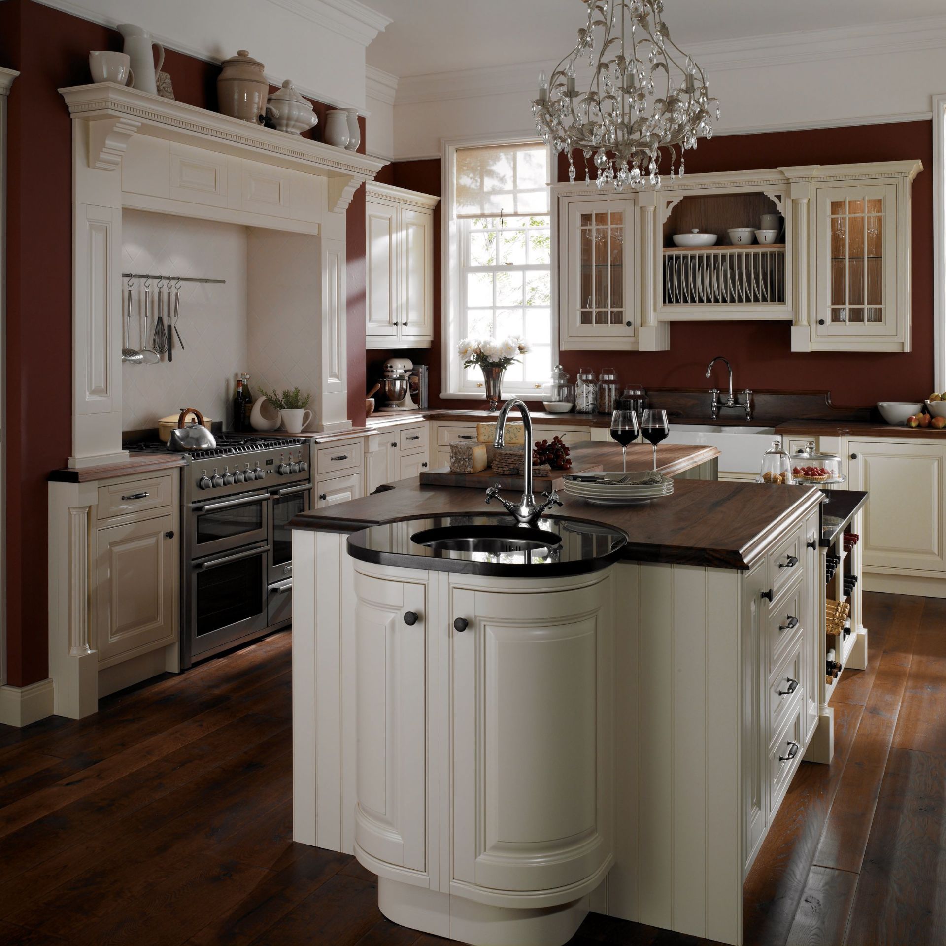Elegante Landhausküche in Creme mit großer Kücheninsel, dunkler Holzarbeitsplatte, integriertem Spülbecken, Gasherd, Vitrinenschränken und Kronleuchter – hochwertiges Küchenmöbel-Design für die Einrichtung