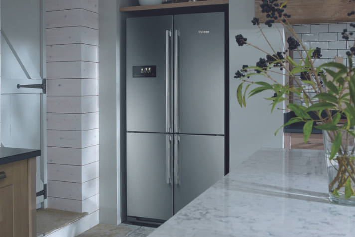 Moderner Edelstahl-Kühlschrank mit French Door Design in stilvoller Küche Großer, moderner Edelstahl-Kühlschrank mit vier Türen steht in einer hell eingerichteten Küche neben einer Arbeitsplatte mit Blumen