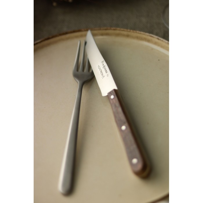 Tischgedeck mit Messer und Gabel auf einem hellen Keramikteller Ein Messer mit Holzgriff und eine Metallgabel liegen auf einem runden, hellen Teller.