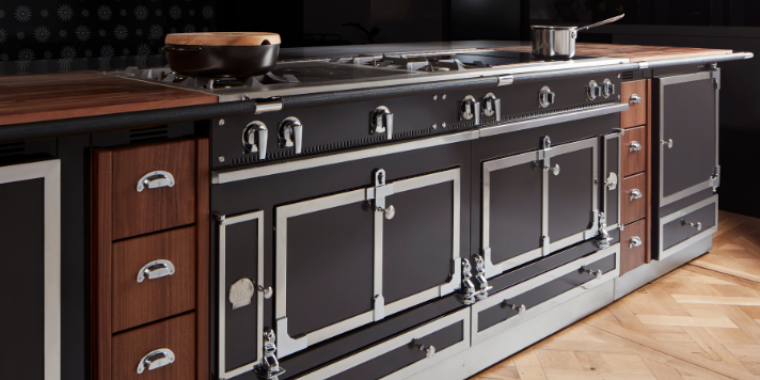 Luxuriöser Küchenherd im Vintage-Design mit Edelstahl- und Holzelementen Küchenherd im edlen, klassischen Design mit schwarzen Oberflächen, silbernen Griffen und Holzverkleidung, auf Parkettboden stehend