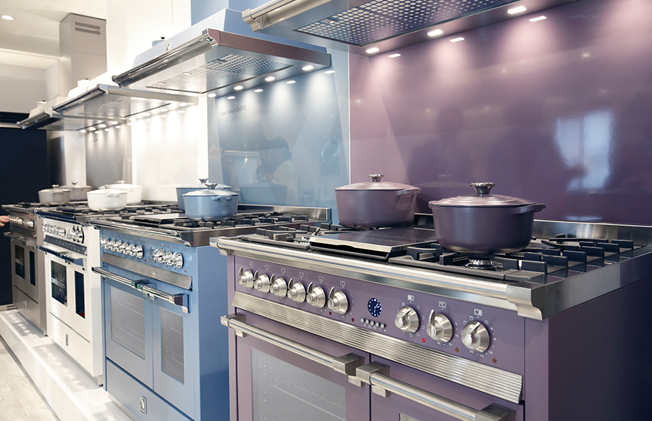 Moderne farbige Standherde mit Gaskochfeldern und Backöfen in einer Küchenausstellung Reihe hochwertiger, farbiger Standherde mit mehreren Gaskochfeldern und Töpfen in einer modernen Küchenausstellung