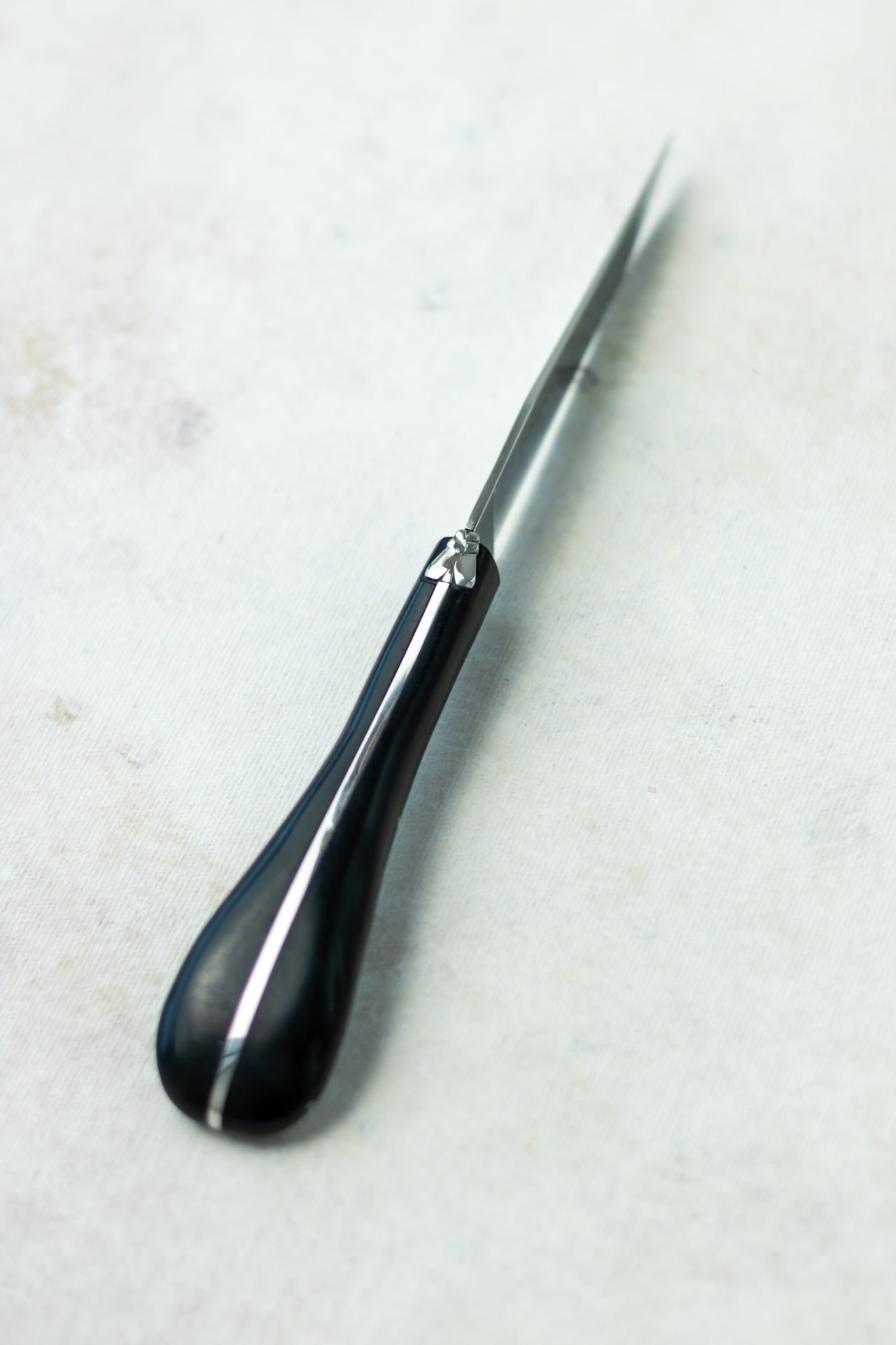 Eleganter Brieföffner mit schwarzem Griff aus Edelstahl Brieföffner mit ergonomischem, schwarzem Griff und schlanker Edelstahlklinge auf hellem Untergrund
