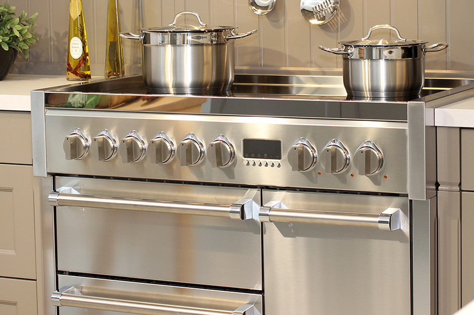 Moderner Edelstahlherd mit Kochplatten und zwei Kochtöpfen in einer stilvollen Küche Ein großer Edelstahlherd mit mehreren Drehknöpfen, zwei silbernen Kochtöpfen und Griffen in einer modernen Küche