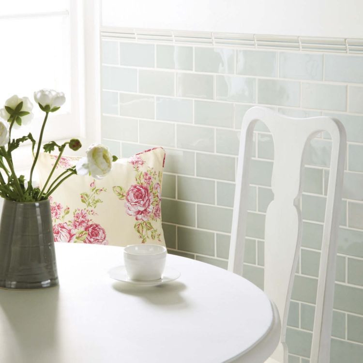 Küche mit pastellgrünen Metrofliesen und weißem Tisch