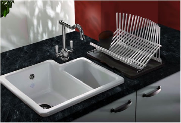 Moderne Küchenspüle mit elegantem Wasserhahn und Abtropfgestell auf schwarzer Arbeitsplatte Weiße Doppelspüle mit verchromtem Wasserhahn und Abtropfgestell für Geschirr auf einer schwarzen Küchenarbeitsplatte