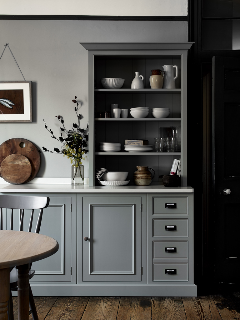 Eleganter grauer Küchenschrank mit offenem Regal und moderner Dekoration in stilvoller Küche Grauer Küchenschrank mit offenen Regalen, gefüllt mit weißen Schalen, Tellern, Tassen und Gläsern, auf Holzfußboden in einer modernen Küche