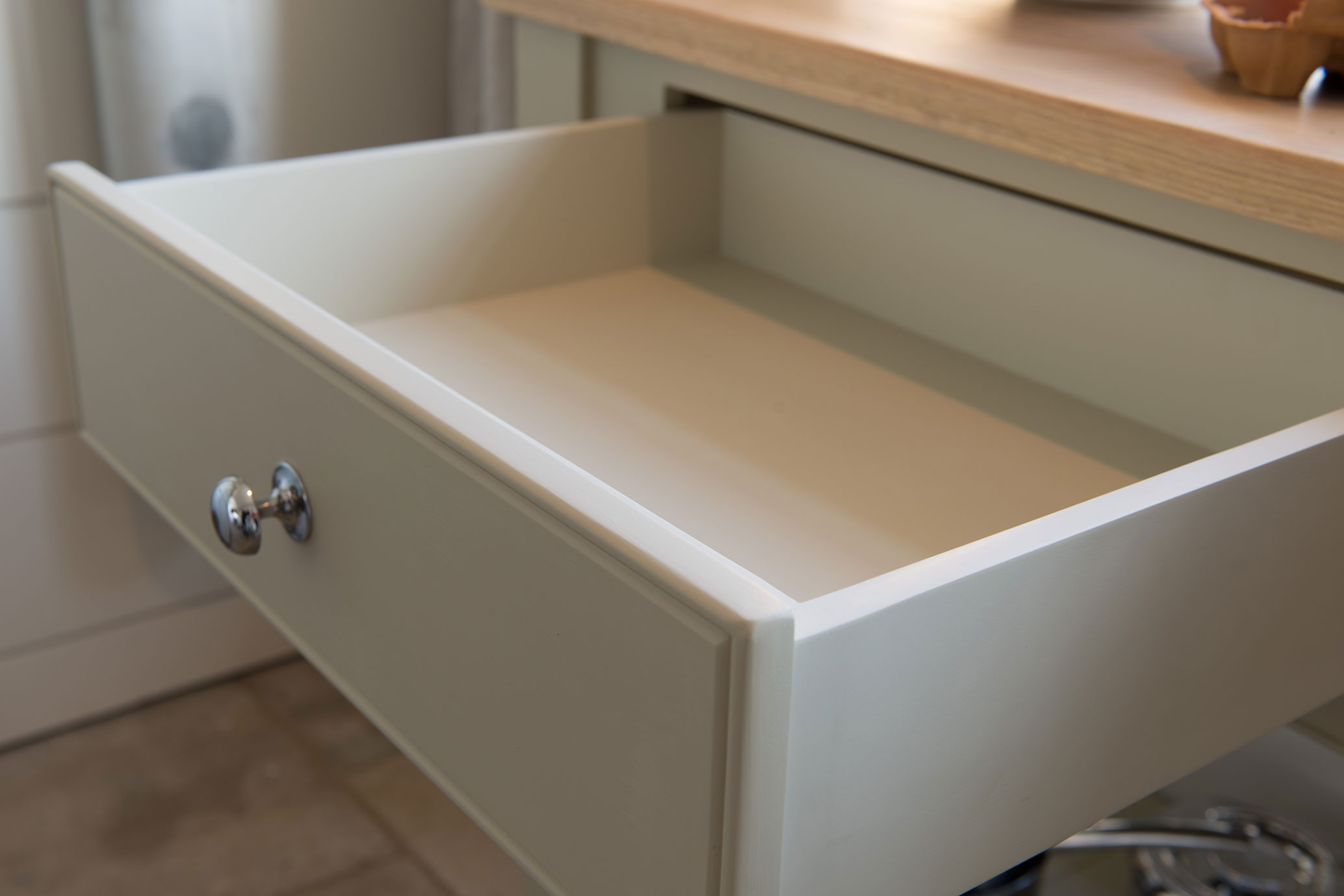 Offene leere Schublade aus Holz mit Metallgriff in moderner Küche Leere, geöffnete Schublade mit silbernem Griff unter einer Holzarbeitsplatte in einer modernen Küche