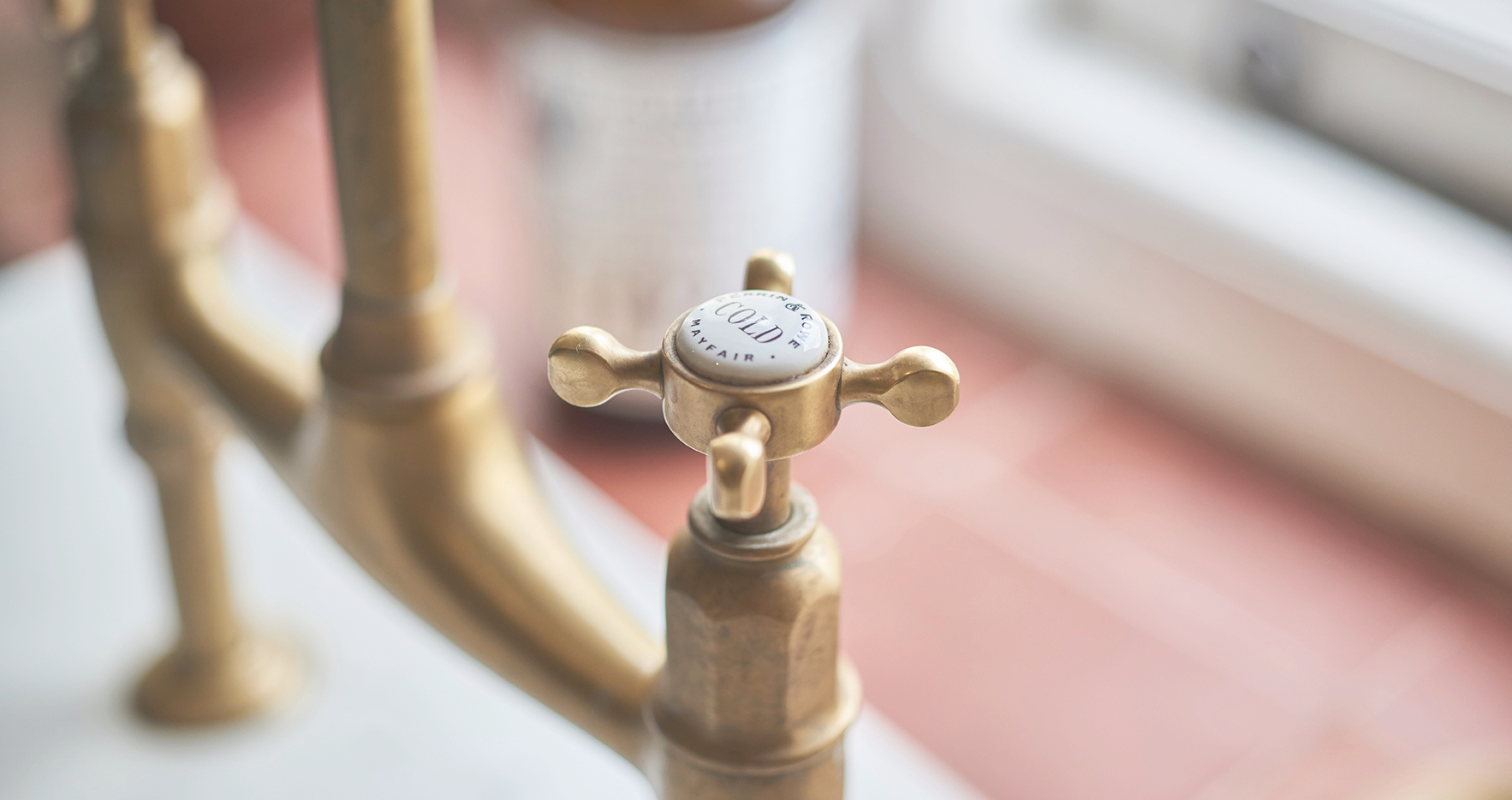 Messing-Wasserhahn im Vintage-Stil mit Kreuzgriff für kaltes Wasser Detailaufnahme eines messingfarbenen Wasserhahns mit Kreuzgriff und Beschriftung 'Cold' für kaltes Wasser, im Retro-Design