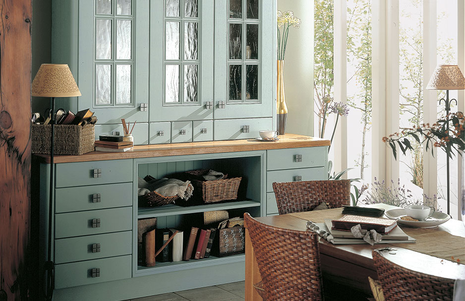 Landhausstil Esszimmer mit hellblauem Buffet und Holztisch Esszimmer mit hellblauem Buffet, Glasvitrinen, Holztisch, geflochtenen Stühlen, natürlicher Beleuchtung und dekorativen Accessoires im Landhausstil.