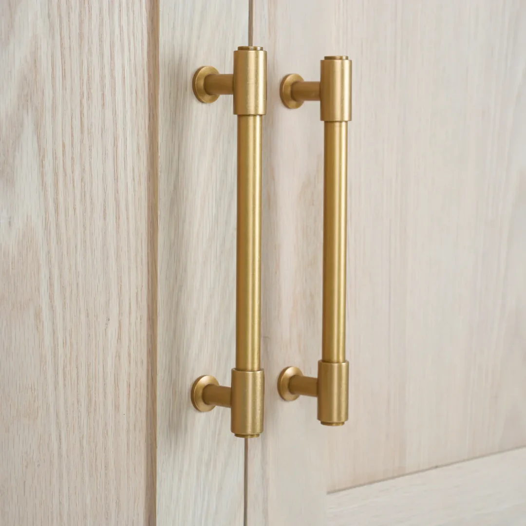 Zwei goldene Messing-Griffstangen an heller Holztür – modernes Möbelgriff-Set für Schrank oder Küche, matt gebürstet