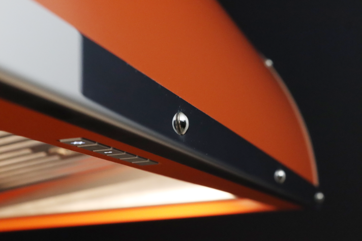 Moderne orange Dunstabzugshaube mit Beleuchtung – Detailansicht Detailaufnahme einer modernen orangenen Dunstabzugshaube mit LED-Beleuchtung und Bedienelementen