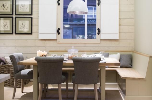 Gemütliche Essgruppe im Landhausstil mit grauen Stühlen, Holztisch und Eckbank vor Fenster mit weißen Fensterläden Esszimmer mit Holzbank, grauen Stühlen, Holztisch, Deko-Kerzen und Fenster mit weißen Läden im Landhausstil