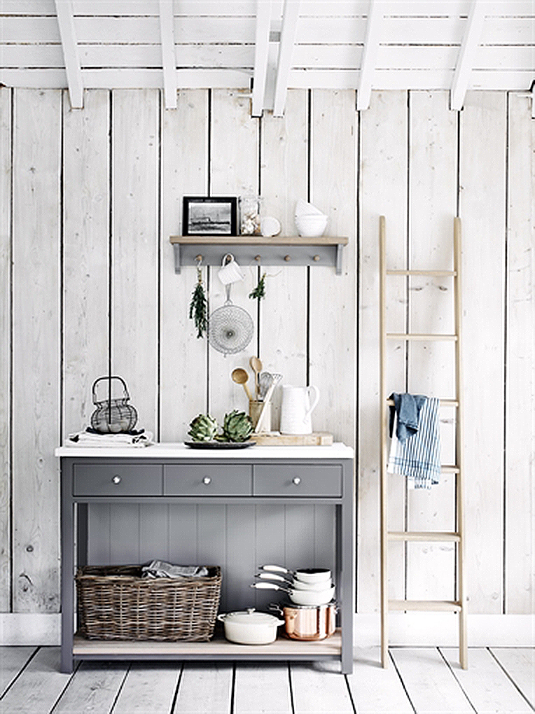 Skandinavische Küchenzeile mit grauem Sideboard, Deko und Leiter im modernen Landhausstil Graues Sideboard mit Küchengeschirr und Korb, dekorative Holzleiter, rustikale Wandverkleidung im skandinavischen Stil