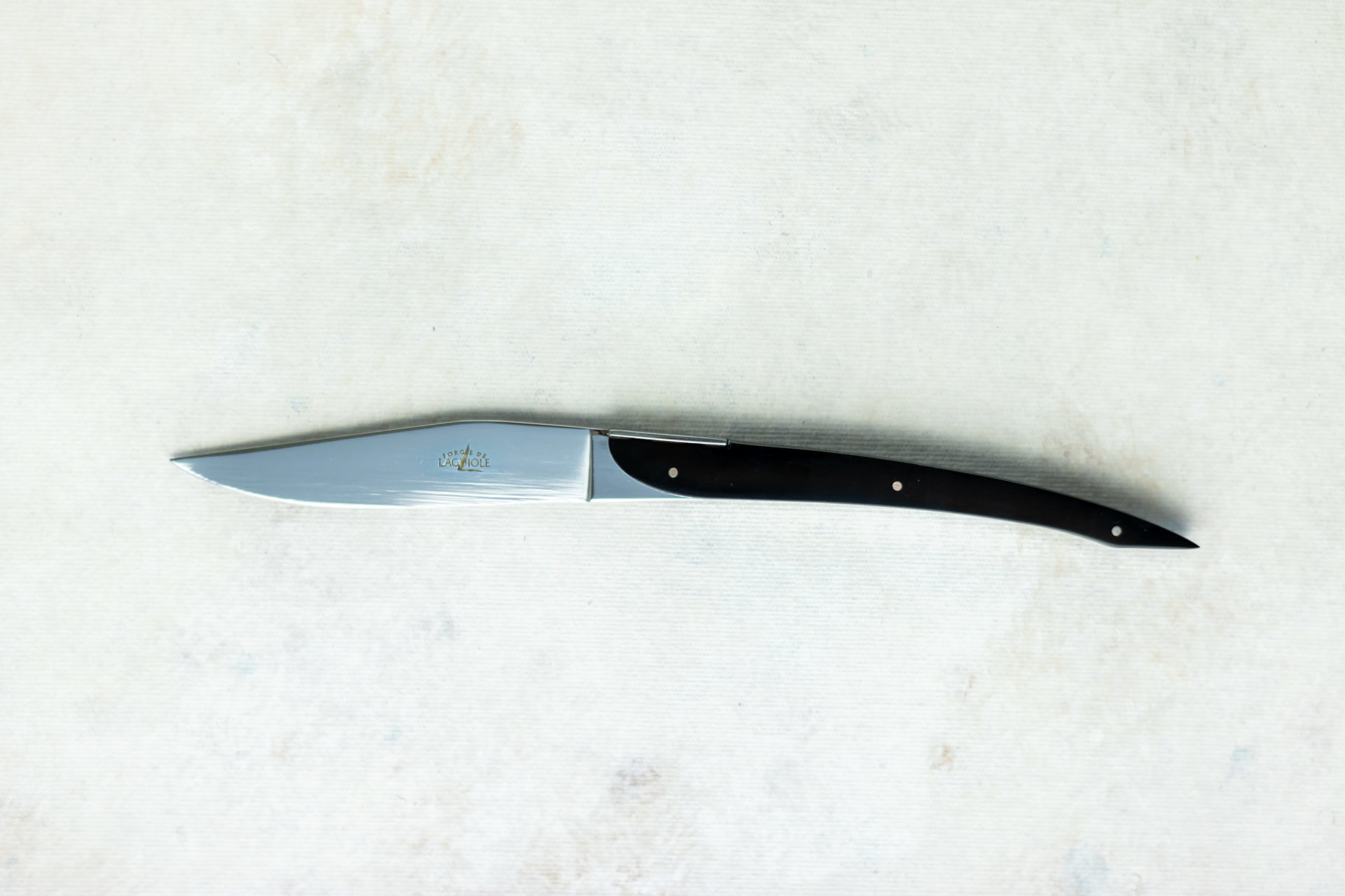 Elegantes Laguiole Steakmesser mit schwarzem Griff – Hochwertiges Edelstahlmesser für Küche und Tisch Modernes Laguiole Steakmesser mit schwarzem Griff und Edelstahlklinge, auf hellem Hintergrund liegend