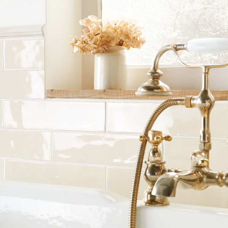 Messing-Badarmatur an Wanne, cremefarbene Fliesen