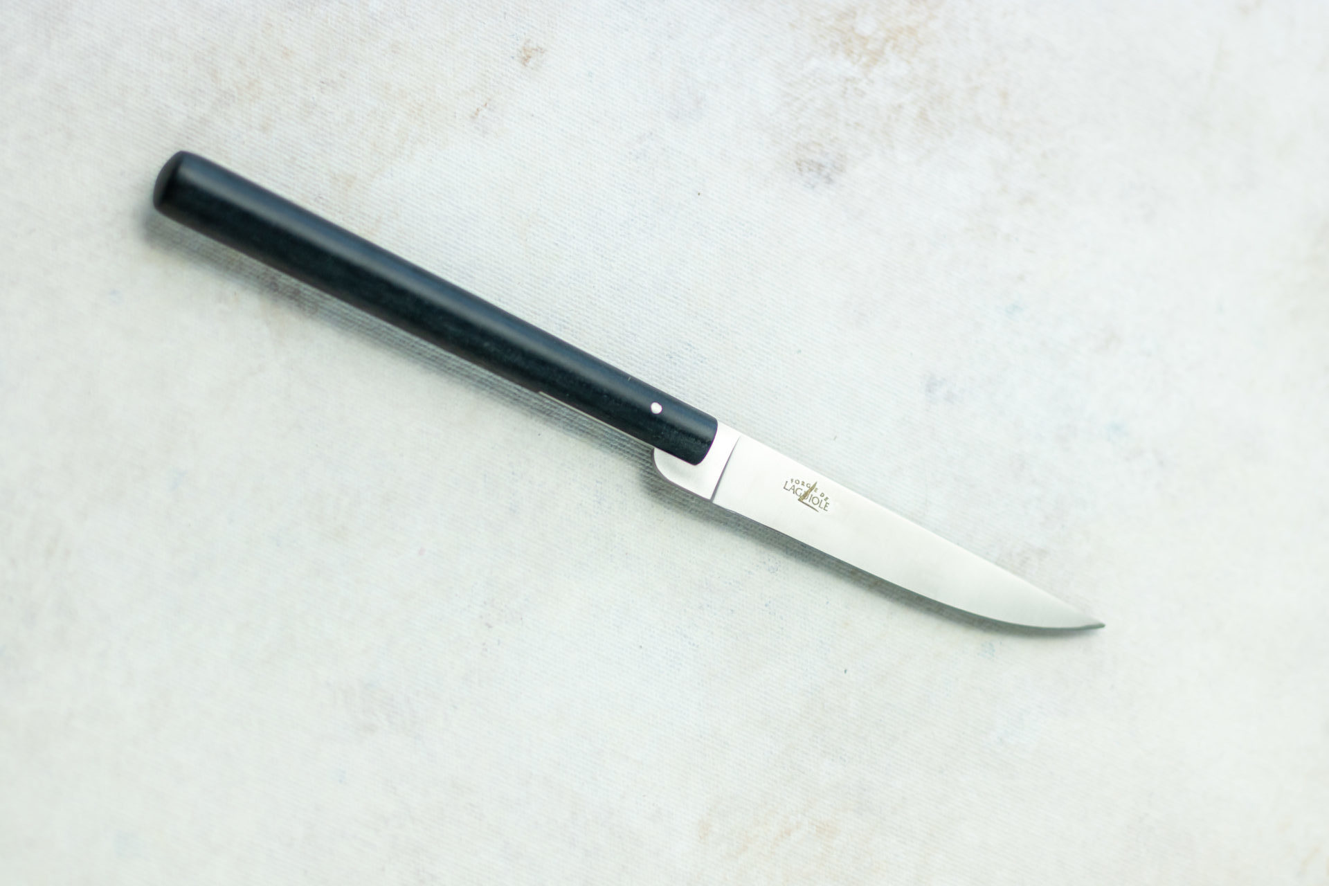 Hochwertiges Laguiole Messer mit schwarzem Griff – ideal als Küchen- oder Steakmesser Abgebildet ist ein elegantes Laguiole Messer mit schwarzem, rundem Griff und glänzender Edelstahlklinge auf hellem Untergrund