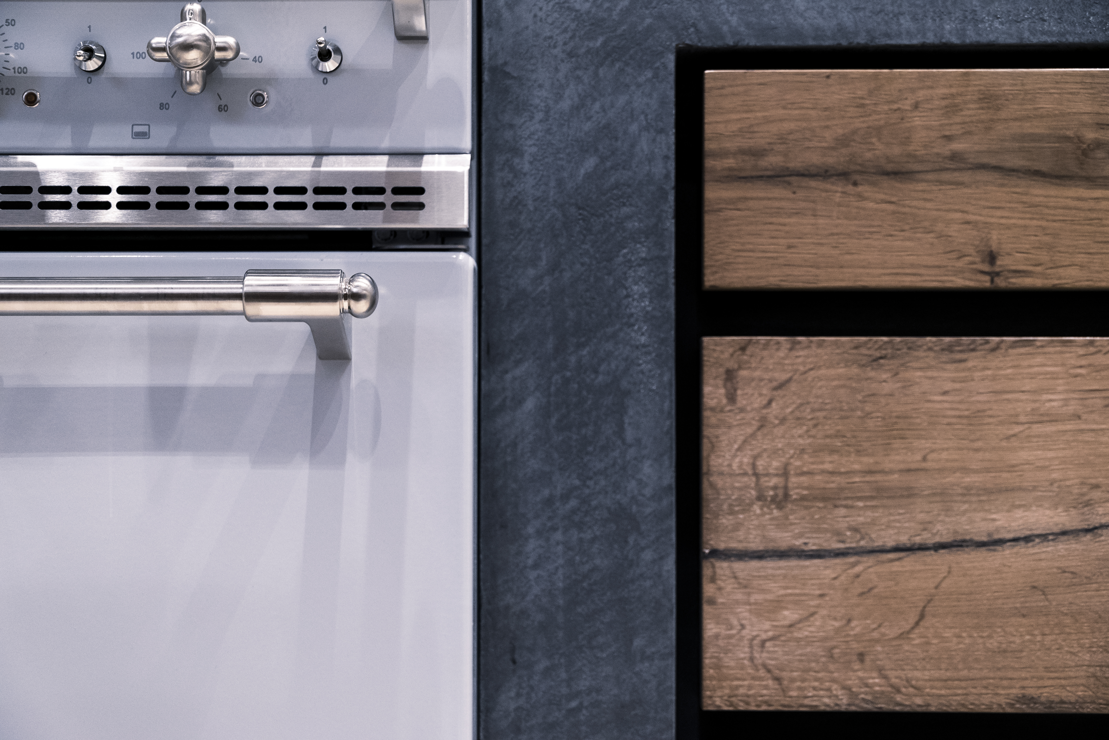 Detailansicht eines modernen Backofens mit Edelstahlgriff und Holzverkleidung im minimalistischen Design