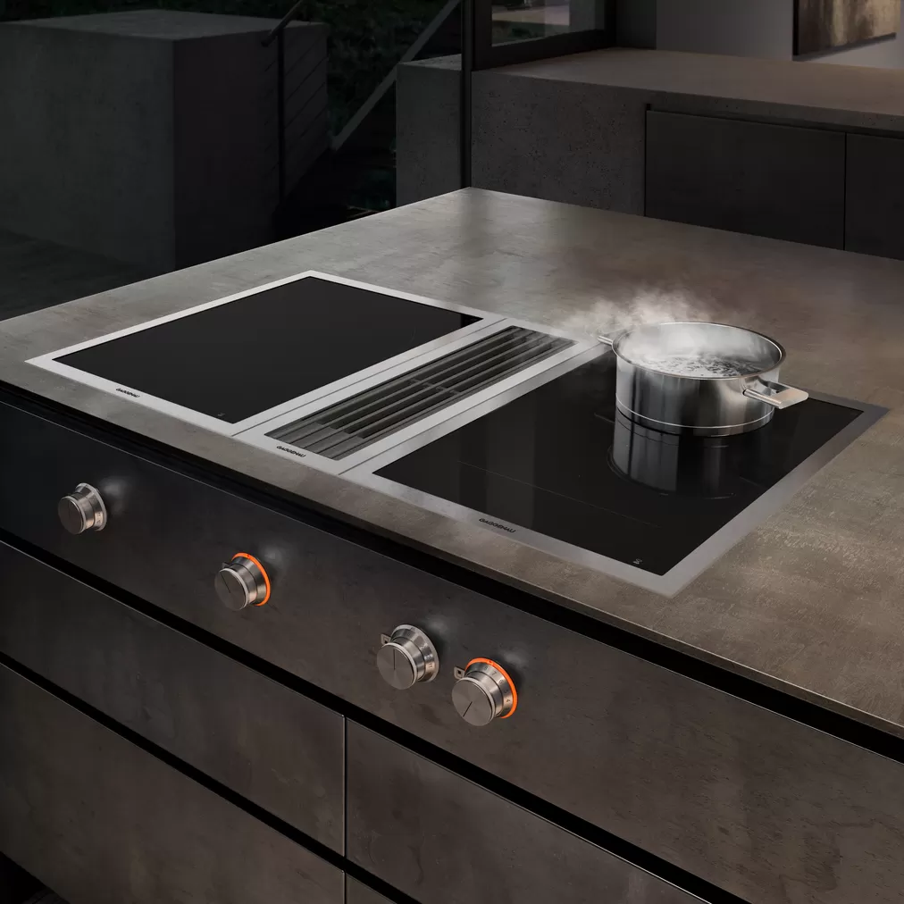 Modernes Induktionskochfeld mit integriertem Dunstabzug in einer Designerküche Induktionskochfeld mit integriertem Dunstabzug in moderner Küche, Topf mit kochendem Wasser auf dem Herd
