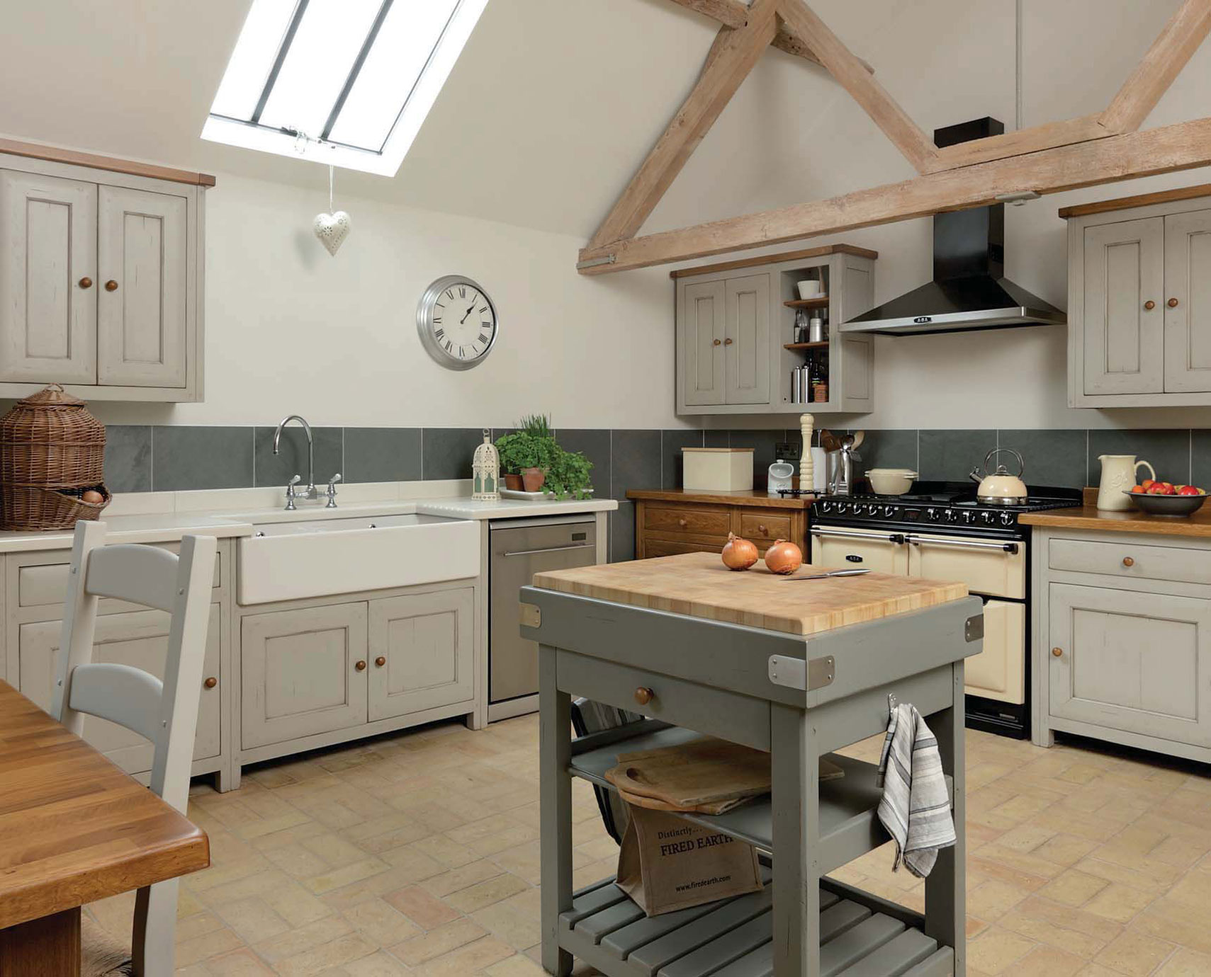 Gemütliche Landhausküche mit Kochinsel, Einbauherd und modernem Interieur Helle Landhausküche mit Holzbalken, großer Arbeitsfläche, klassischem Herd und Kücheninsel aus Holz