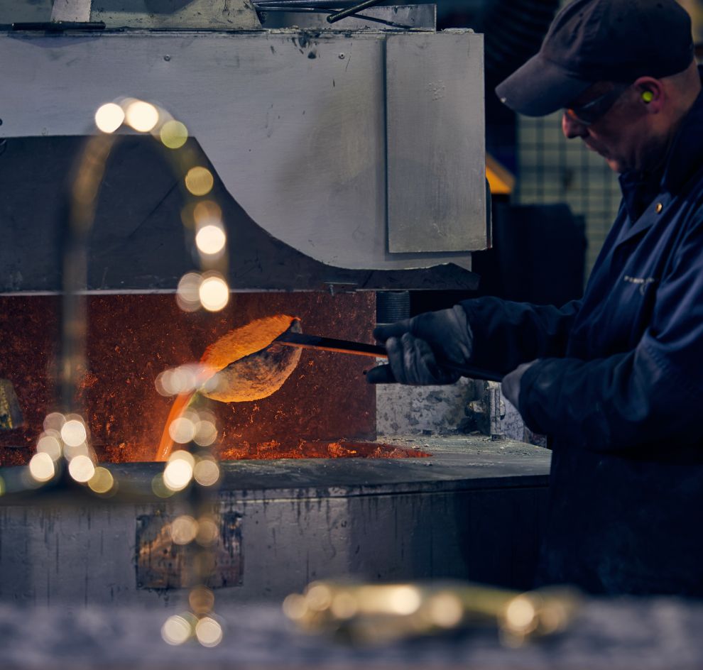 Gießer schüttet flüssiges Metall, vorne Messingarmatur