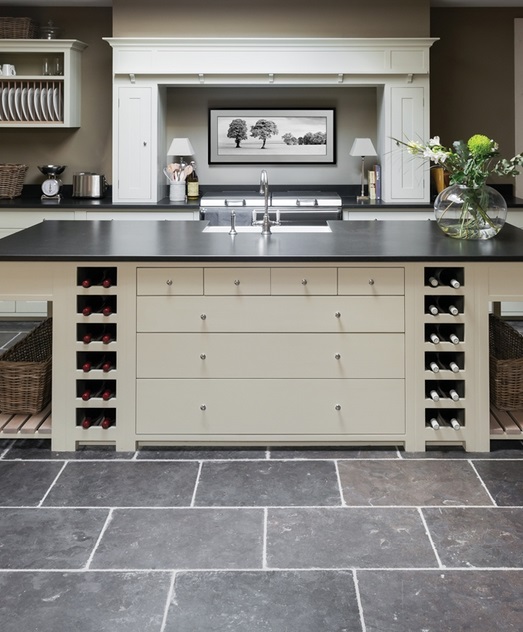 Moderne Küche mit Kochinsel, Weinschränken und stilvollem Dekor Elegante, helle Küche mit Kochinsel, schwarzen Arbeitsplatten, eingebauten Weinfächern, Spüle, dekorativer Vase und ruhigem Wandbild im Hintergrund