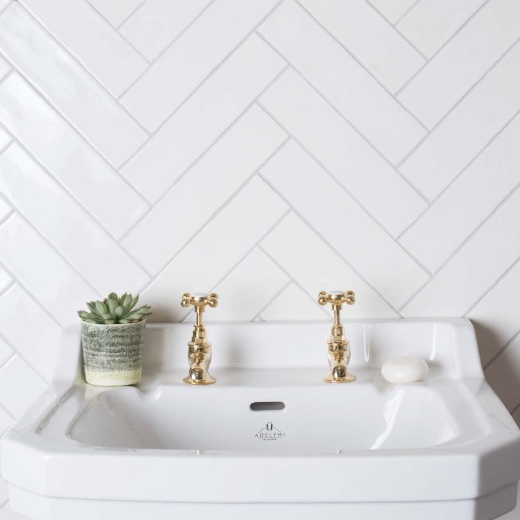 Keramik-Waschbecken, goldene Wasserhähne, weiße Fliesen