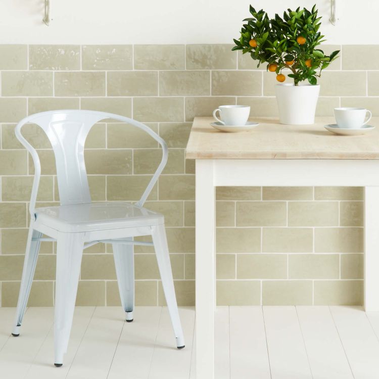 Heller Metallstuhl neben Tisch, Pflanze und Tassen