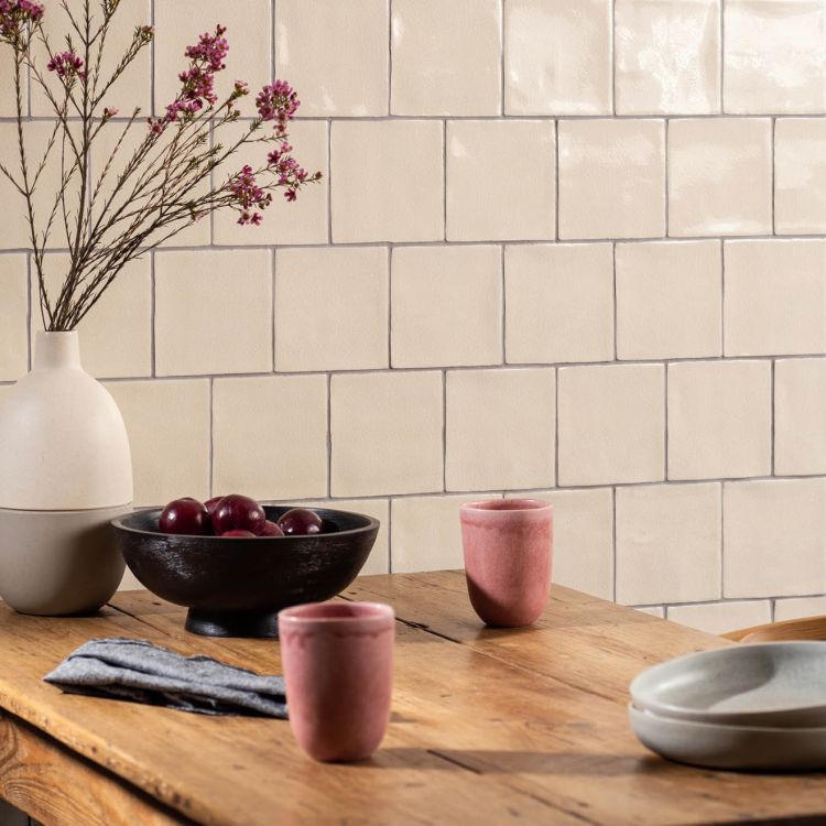 Beige Fliesenwand, Holztisch mit Keramik und Pflaumen