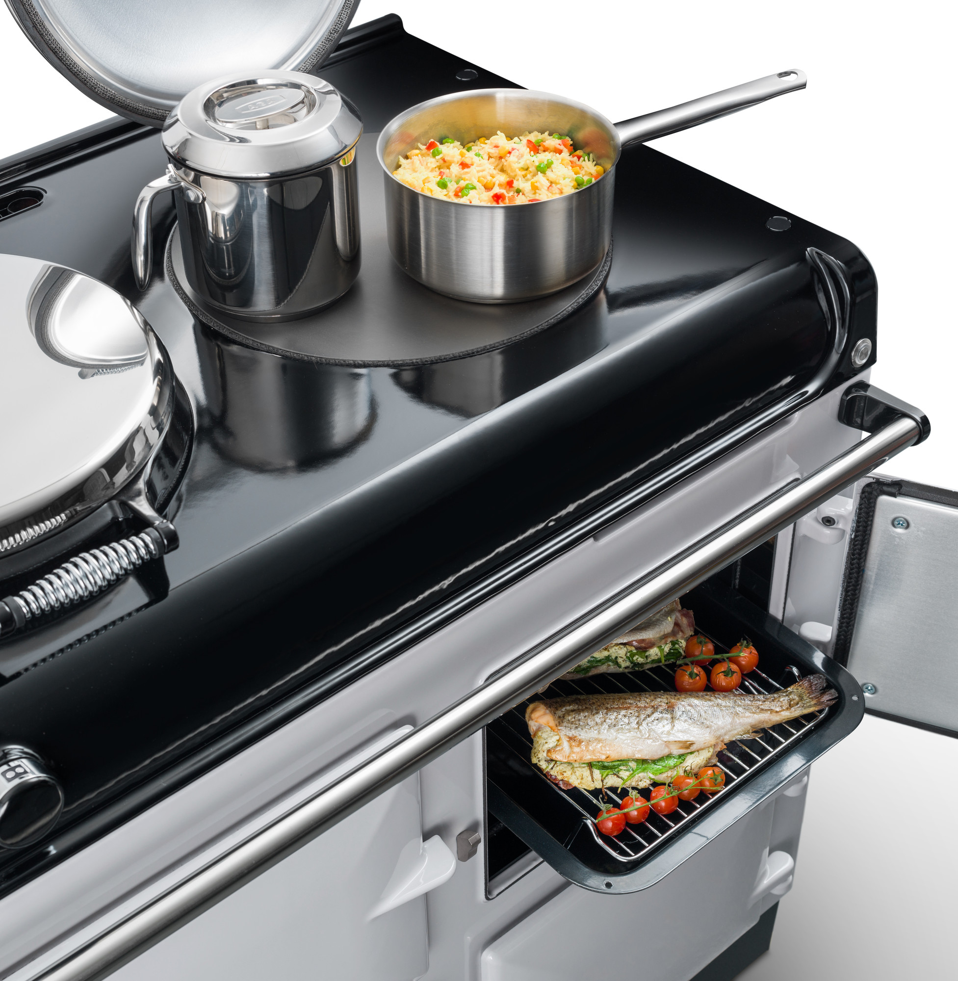 Hochwertiger Küchenherd mit Backofen, frischer Fisch und Gemüse im Ofen sowie Kochtopf und Kanne auf dem Kochfeld Detailaufnahme eines modernen Küchenherds, mit einem Backofen, in dem Fisch und Tomaten garen, und einem Kochtopf mit Gemüse-Reis sowie einer Kanne auf dem Kochfeld