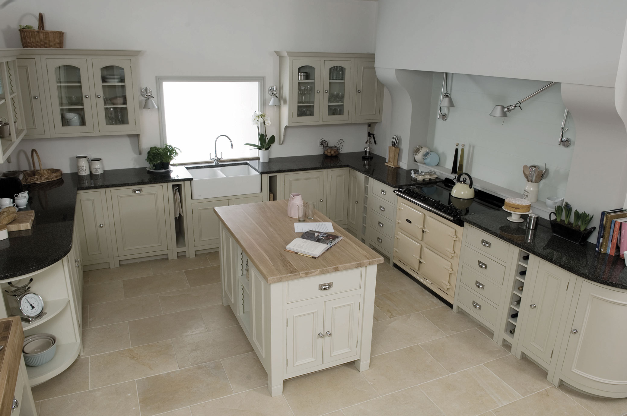 Helle Landhausküche mit Kochinsel, cremefarbenen Einbauschränken und Granit-Arbeitsflächen Großzügige Landhausküche in hellen Tönen mit zentraler Kücheninsel, Steinfliesenboden, cremefarbenen Schränken, modernem Herd und Doppelspülbecken