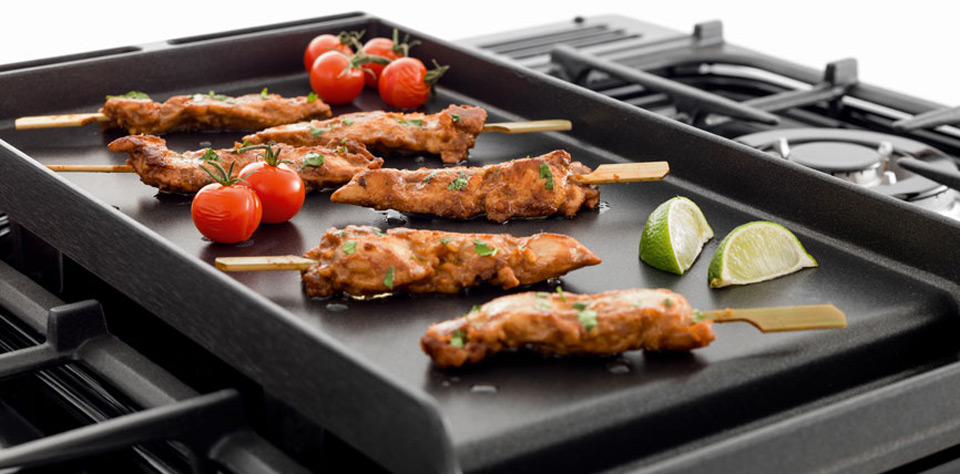 Grillplatte für Gasherd mit Hähnchenspießen, Kirschtomaten und Limettenspalten – Perfekt zum Braten und Grillen Schwarze Grillplatte auf Gasherd mit gegrillten Hähnchenspießen, frischen Kirschtomaten und Limettenspalten