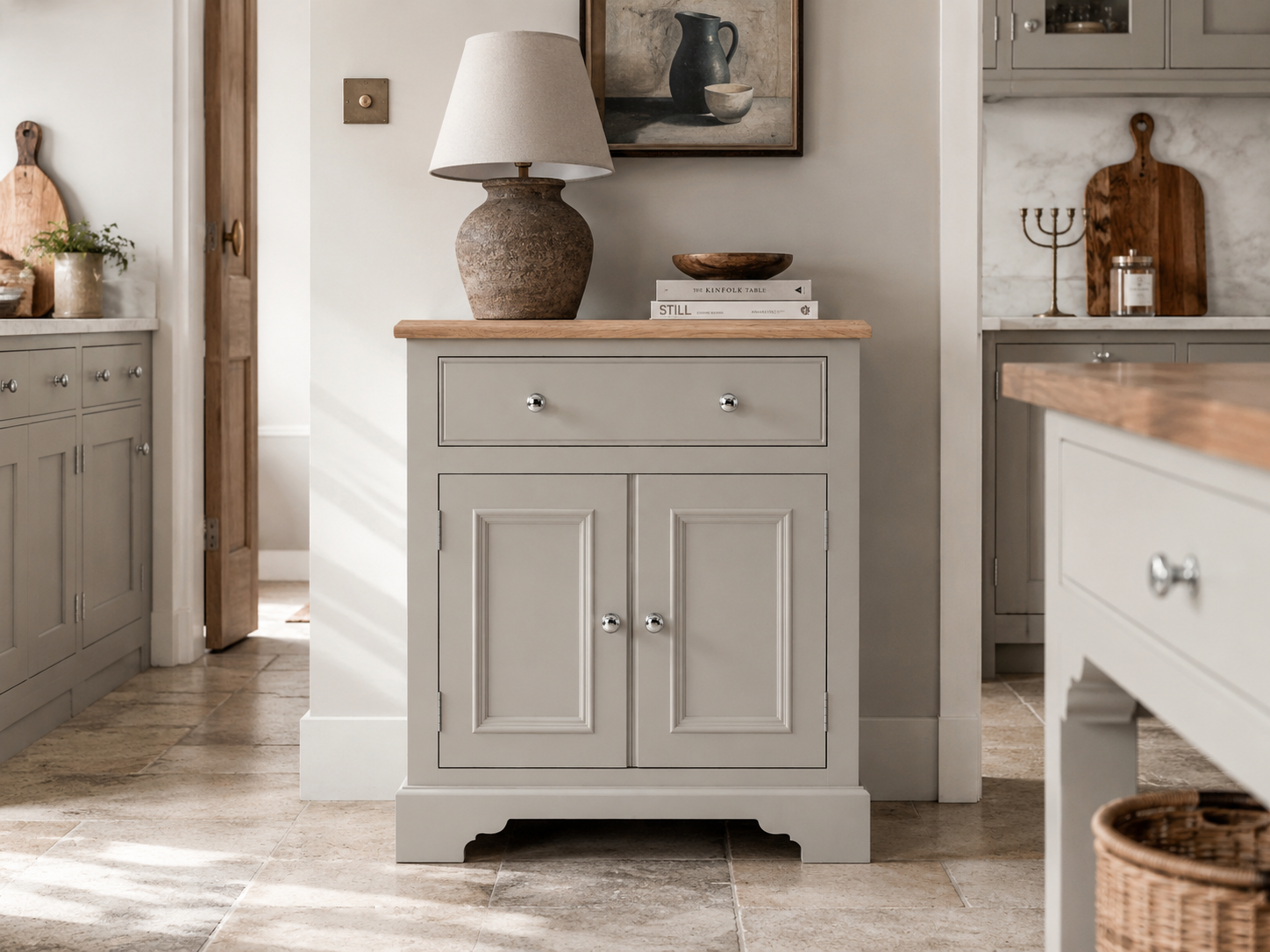 Freistehende graue Küchenkommode im Shaker-Stil mit Eichenplatte, Schublade und Doppeltür; dekoriert mit Keramiklampe und Holzschale in heller Landhausküche
