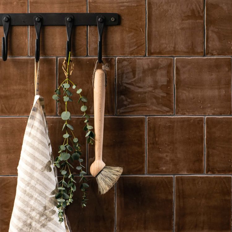 Wandhaken vor braunen Fliesen mit Bürste und Tuch
