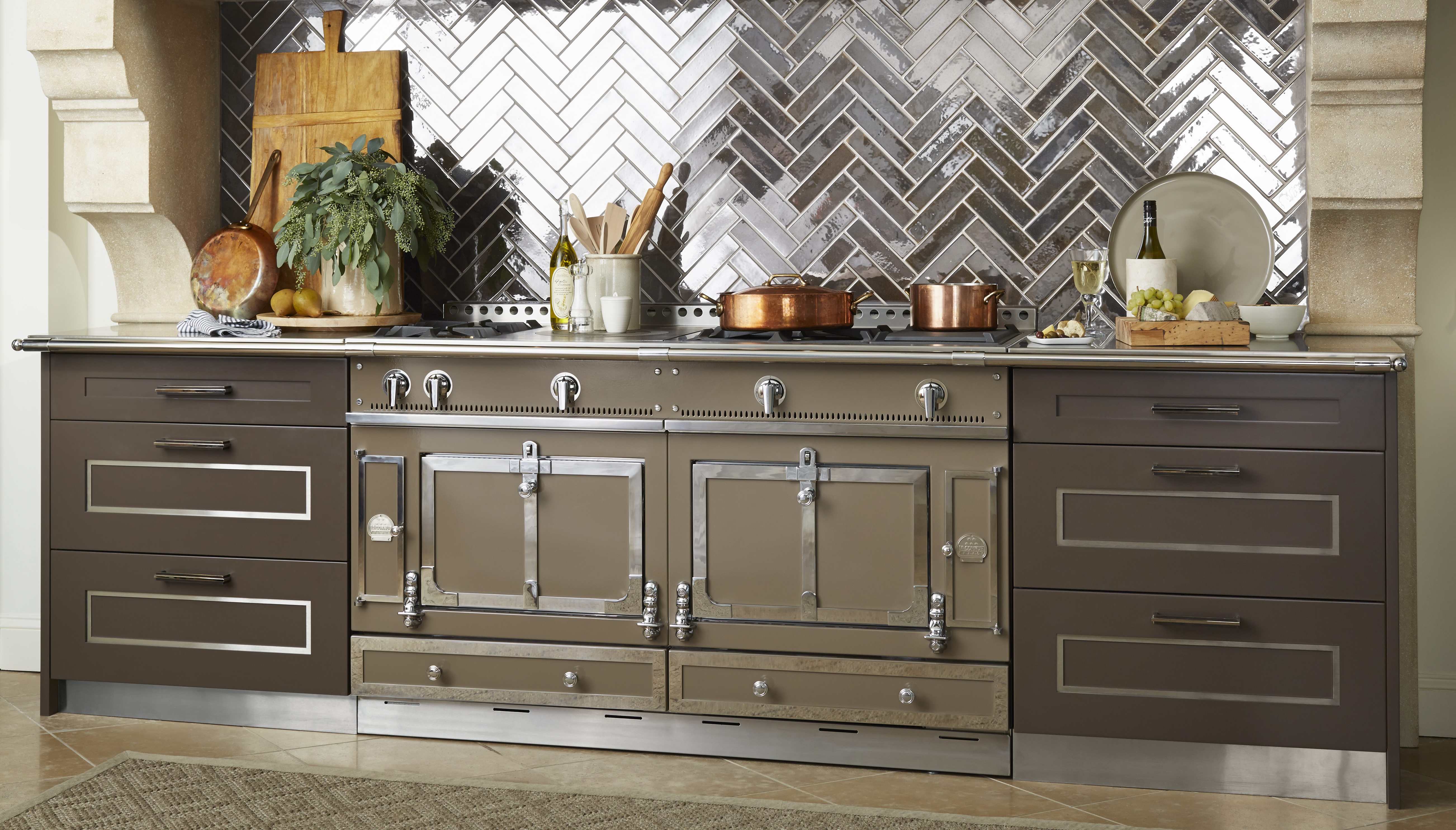 Luxuriöser Herd in moderner Landhausküche mit Kupfertöpfen und stilvoller Fliesenrückwand Großer Premium-Küchenherd mit Kupfertöpfen, Küchenutensilien, Schneidebrett, und Fliesenrückwand in einer eleganten Einbauküche