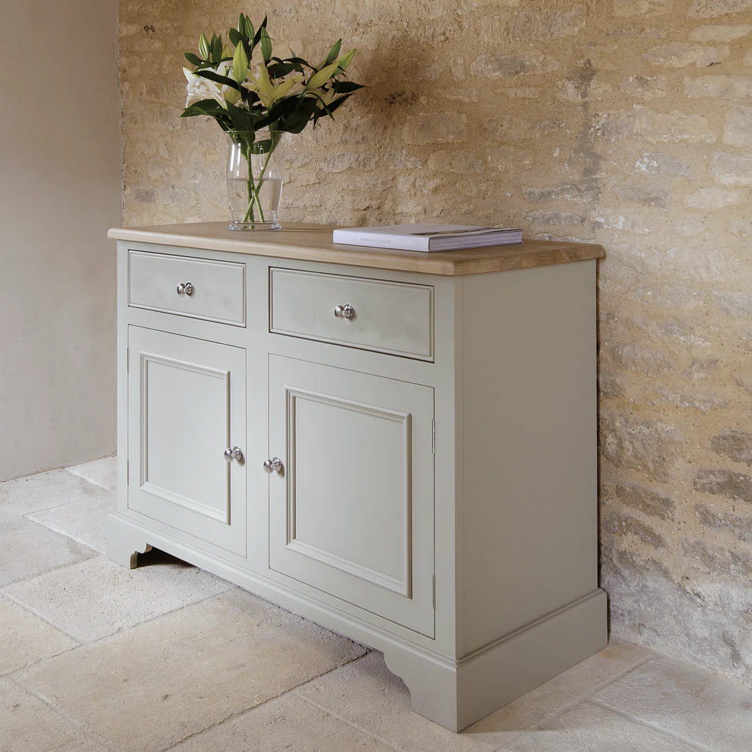 Graues Sideboard im Landhausstil mit massiver Eichenplatte, 2 Schubladen und 2 Türen, Metallknöpfe; dekoriert mit Vase und Buch – ideale Anrichte/Kommode für Wohn- oder Esszimmer