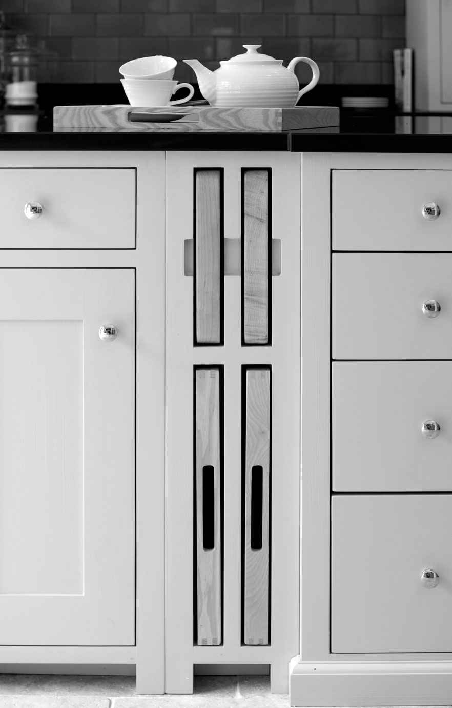 Eleganter weißer Küchenschrank mit integrierten Schneidebrettern und Teeservice auf Tablett Weiße Küchenunterschränke mit herausziehbaren Schneidebrettern, darauf ein Tablett mit Teekanne und Tasse