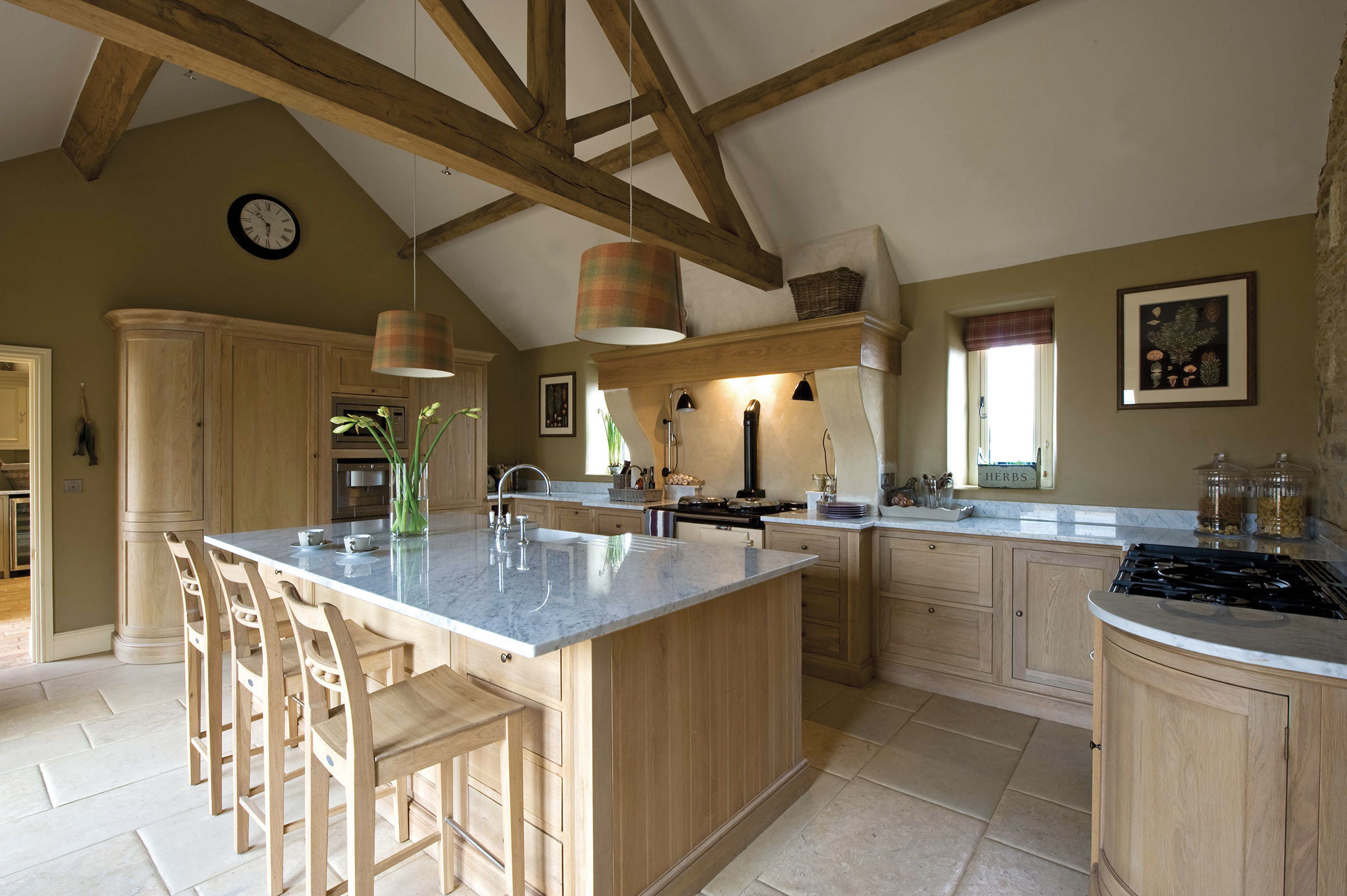 Moderne Landhausküche mit Kücheninsel und Holzelementen Große Landhausküche mit Holzmöbeln, Kücheninsel mit Marmorarbeitsplatte, Holzbalken-Decke und stilvollen Hängelampen