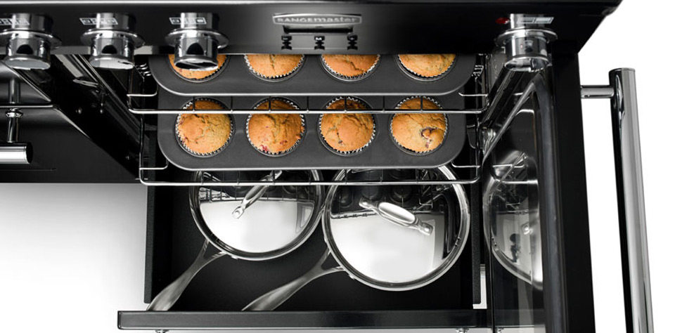 Backofen mit Muffinblech und Kochtöpfen, modernes Küchengerät im Einsatz Offener Backofen mit einem Muffinblech, auf dem acht Muffins gebacken werden, darunter befinden sich zwei glänzende Kochtöpfe mit Deckel auf einem Blech.