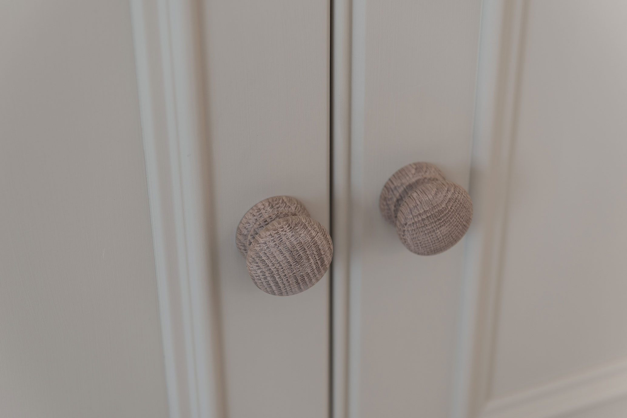 Detailansicht von zwei runden Schrankknäufen aus Holz an einer weißen Schranktür Zwei runde, strukturierte Holzknäufe an einer hellen Schranktür aus nächster Nähe fotografiert